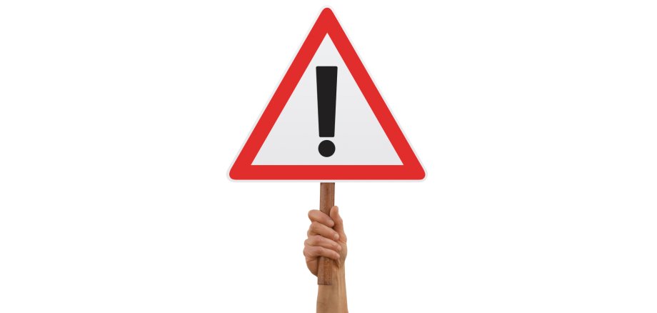 Eine Hand hält ein Warnzeichen nach oben
