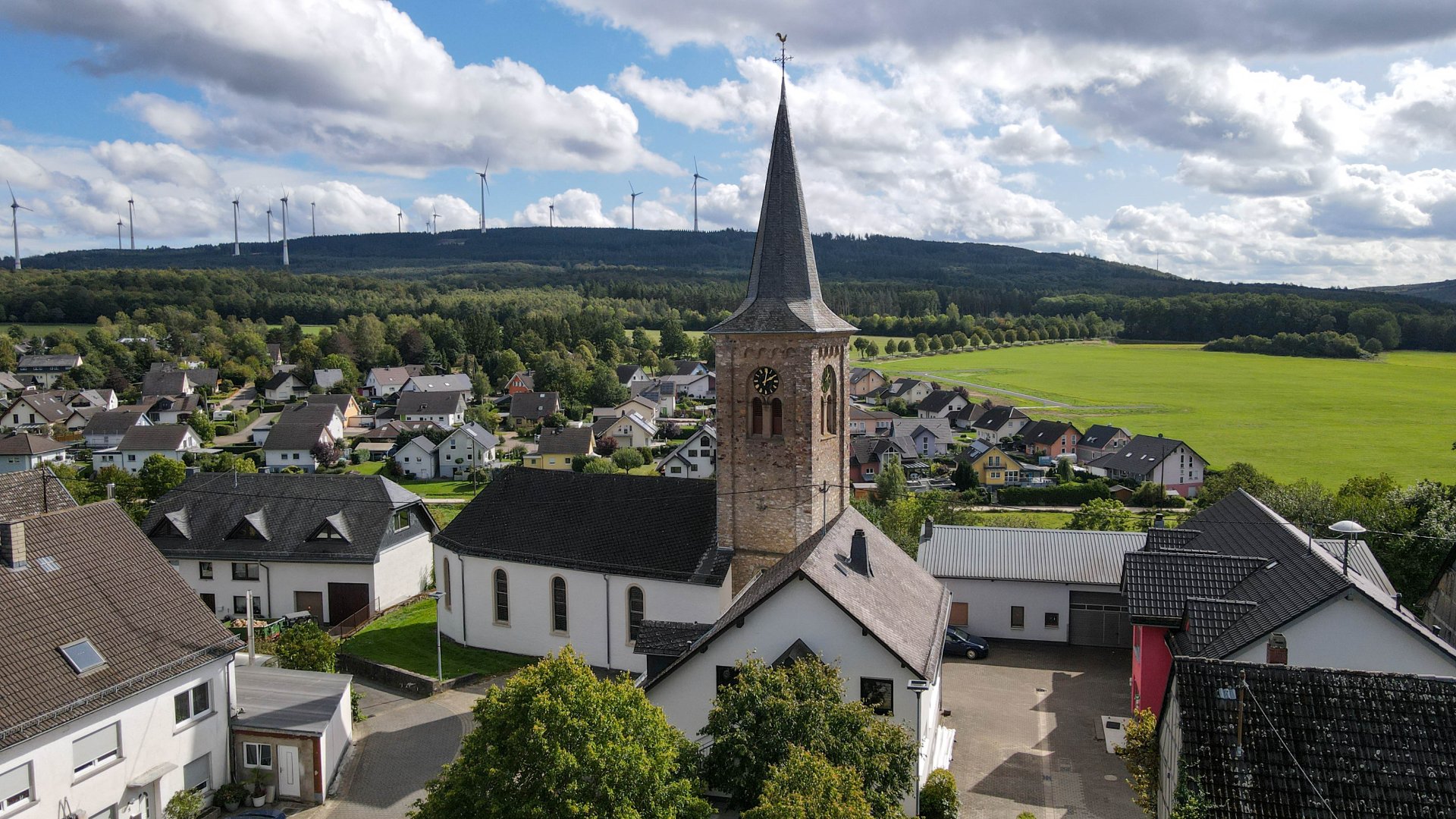 Ortsansicht von oben mit der Kirche im Vordergrund bei schönem Wetter