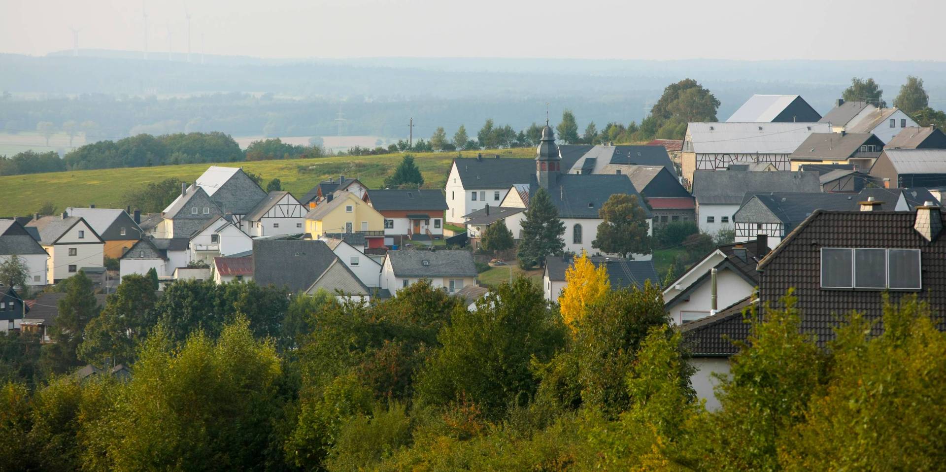 Blick auf die Häuser von Holzbach mit der Kirche im Mittelpunkt bei trübem Wetter