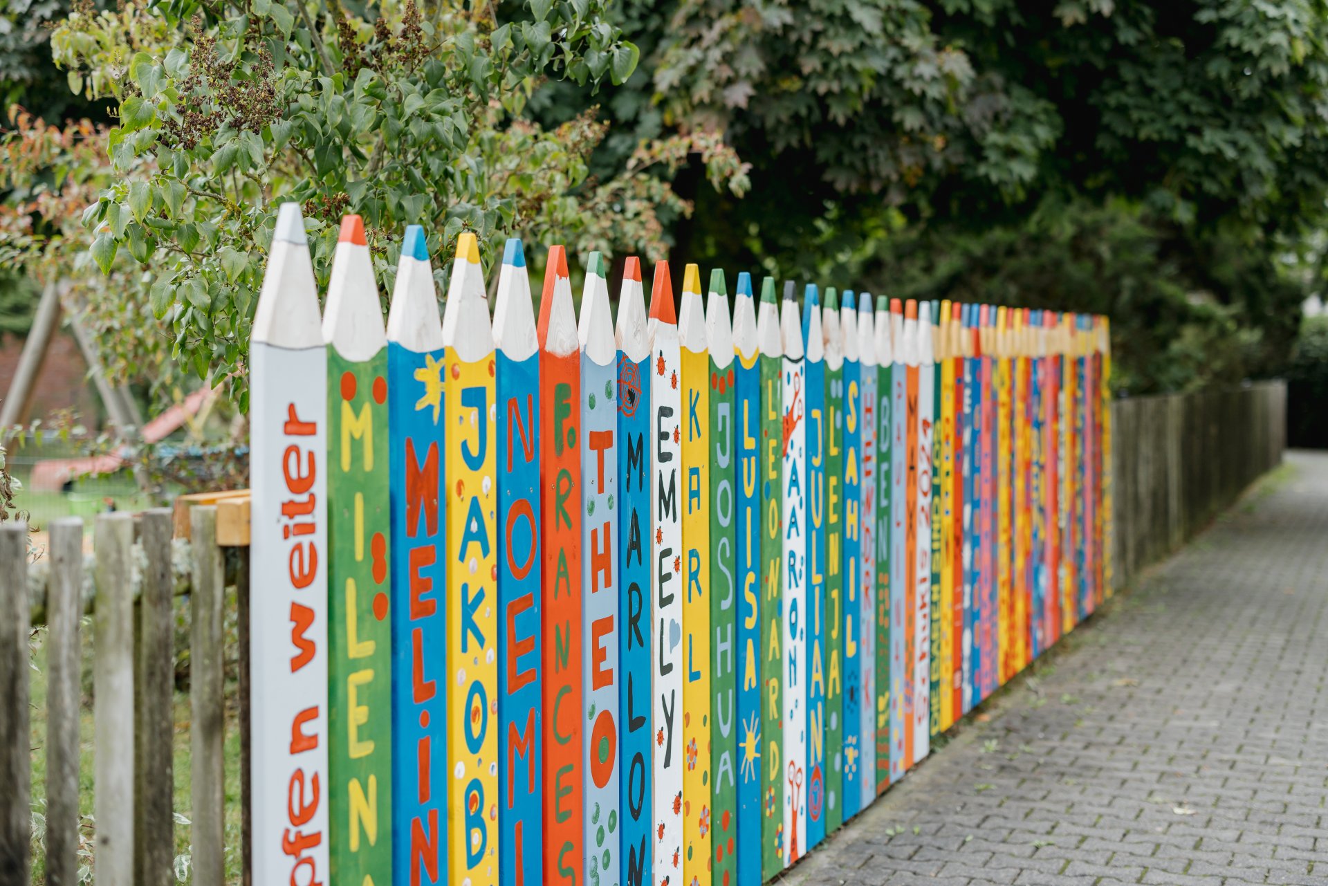 Angemalte große Stifte vor der Kindertagesstätte als Holzelement