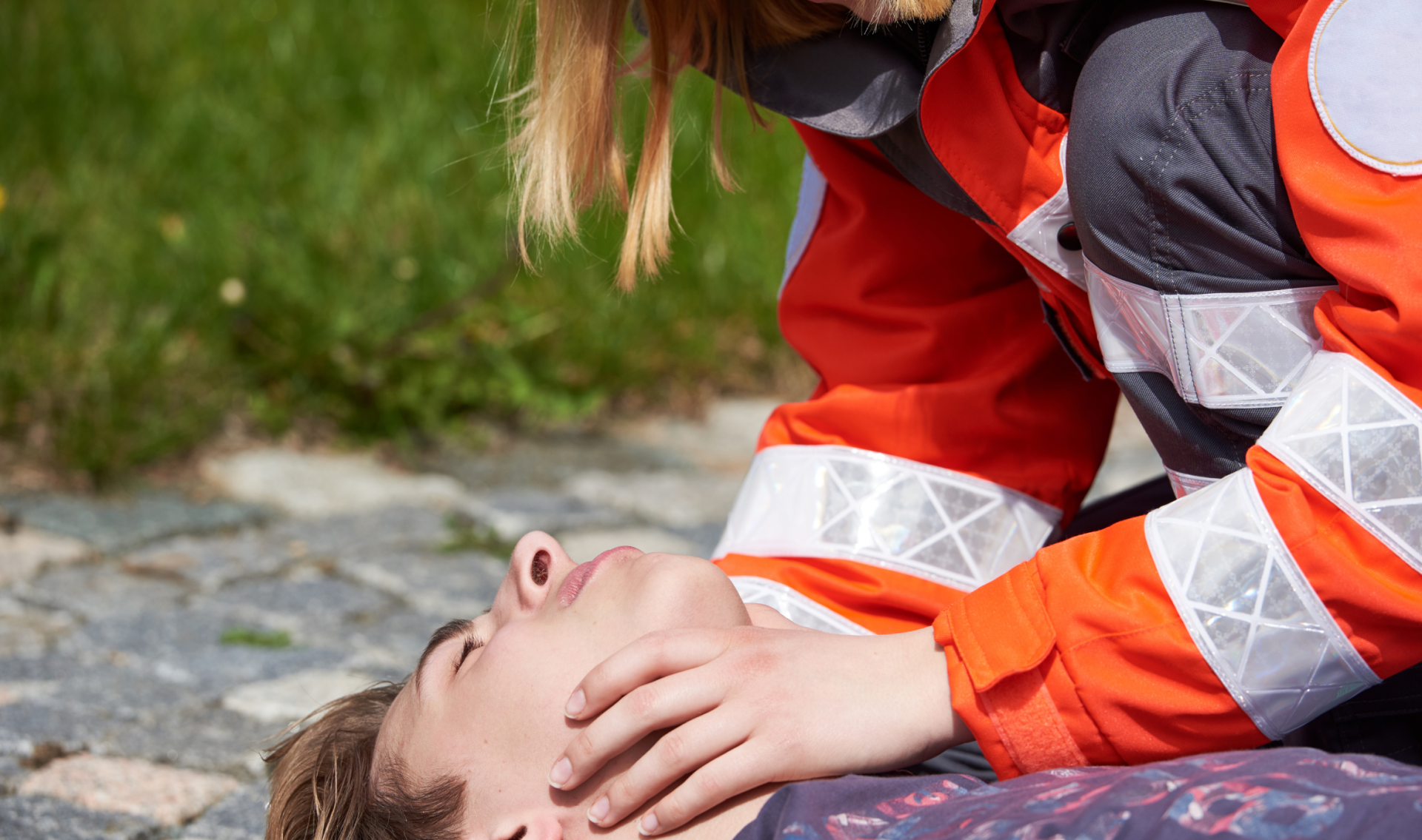 Helfer vor Ort bückt sich über eine Person, die auf dem Boden liegt