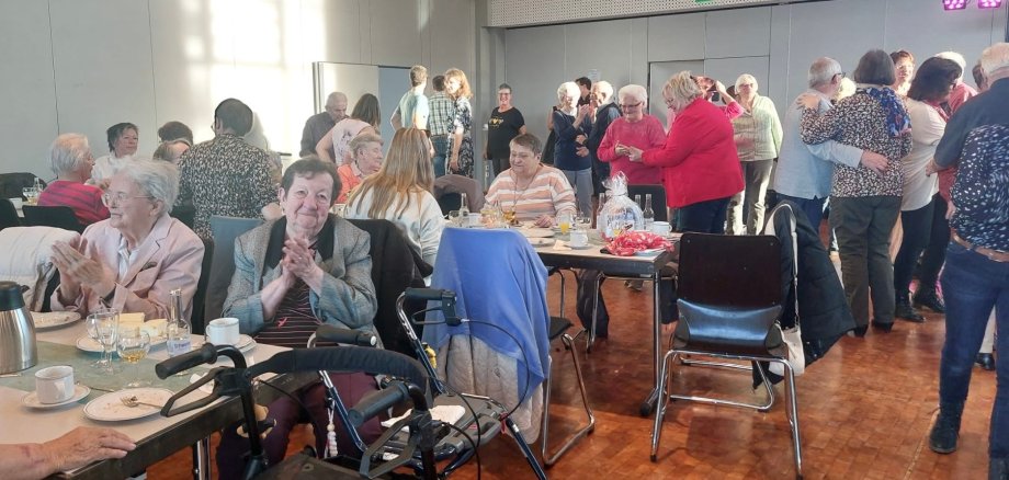 Ältere Damen und Herren sind in der Hunsrückhalle versammelt, essen Kuchen und unterhalten sich.
