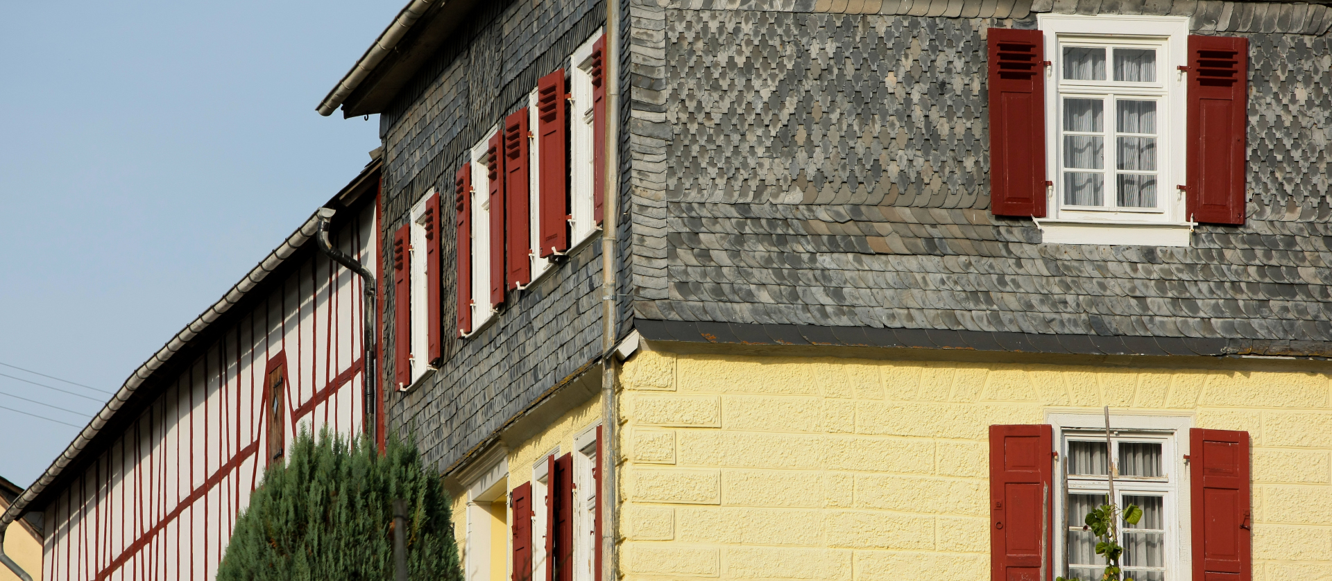 2 Gebäude: Eines mit Fachwerk und das andere verputzt mit Steinen und Fensterläden