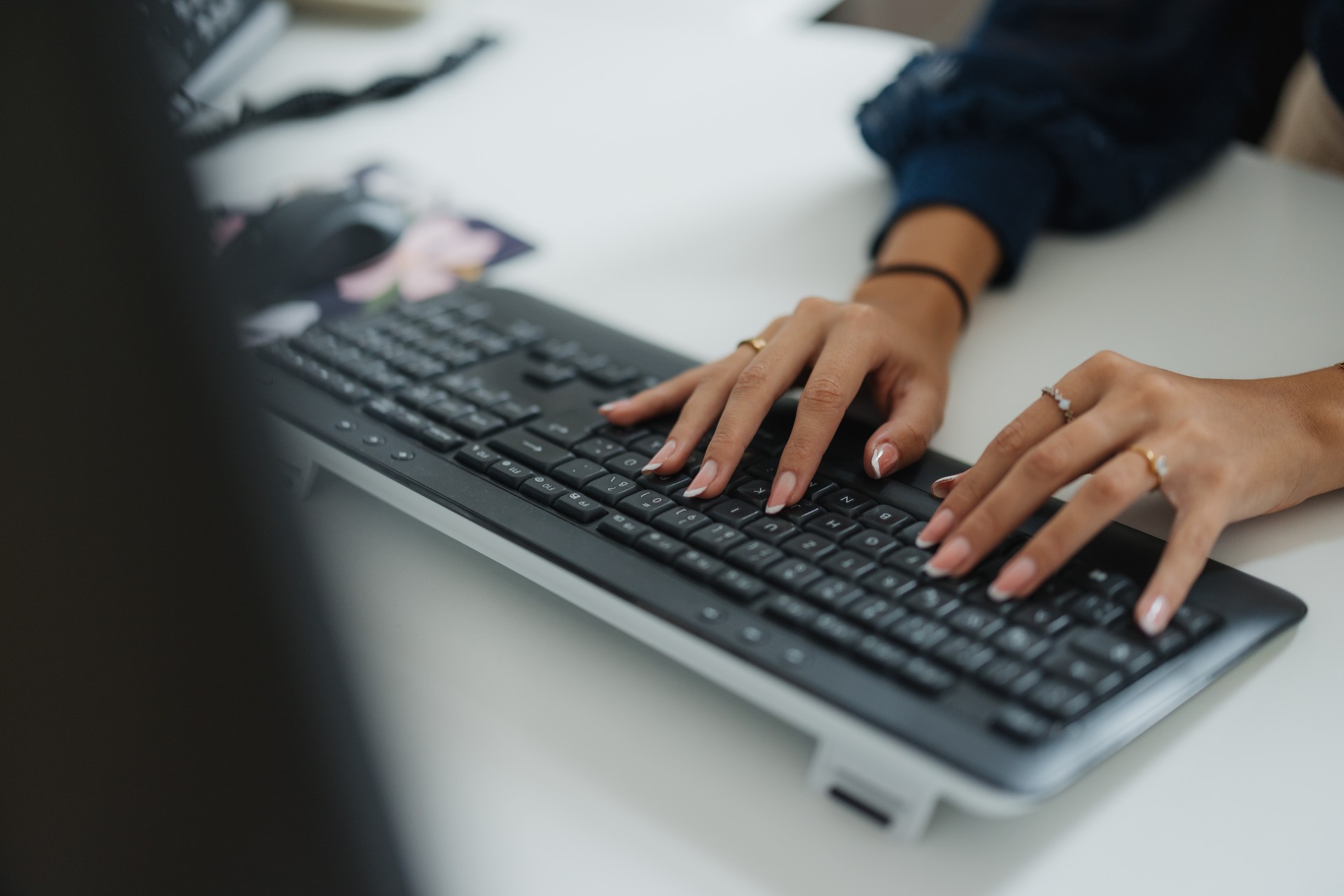 Person sitzt vor einer Tastatur und tippt etwas ein