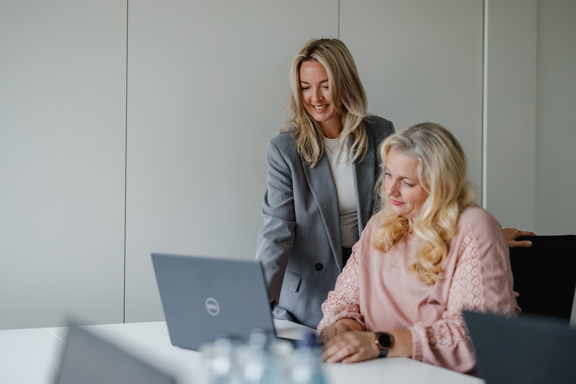 Zwei Mitarbeitende sitzen vor einem Laptop und begutachten den Inhalt auf dem Bildschirm. SIe freuen sich.
