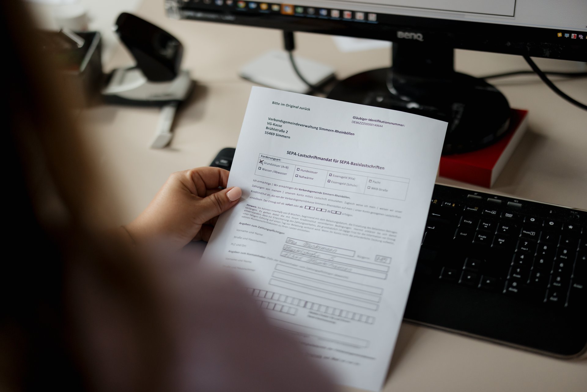 Eine Person hält ein Dokument für ein SEPA-Lastschriftmandat zu gewähren, in der Hand.