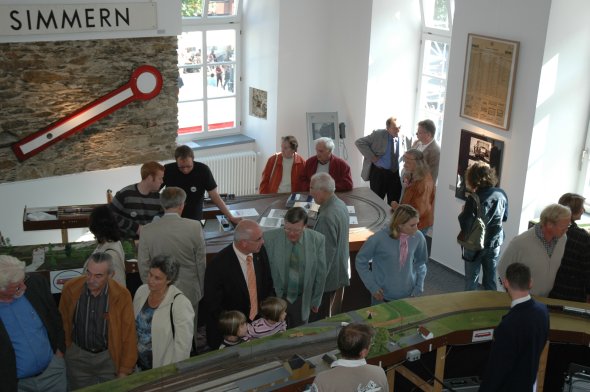 Menschen stehen zusammen und begutachten eine Eisenbahnausstellung.