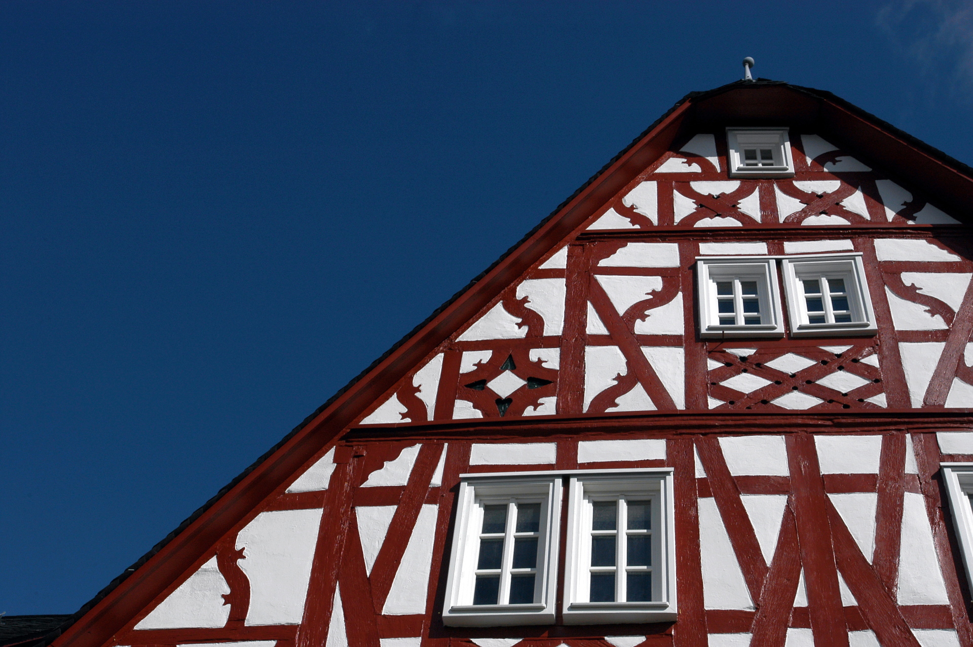 Ein Fachwerkhaus mit roten Balken bei blauem Himmel.