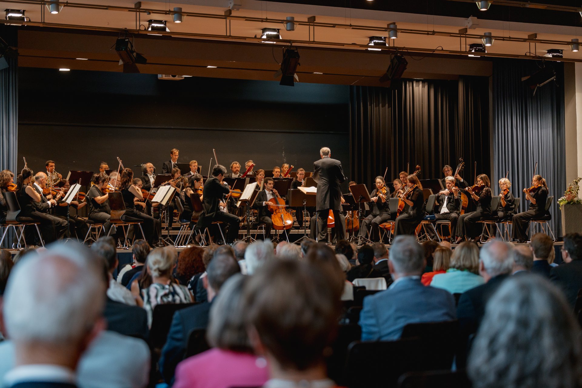 Philharmoniker in der Hunsrückhalle in Simmern musizieren auf der Bühne, das Publikum sitzt vorne dran.