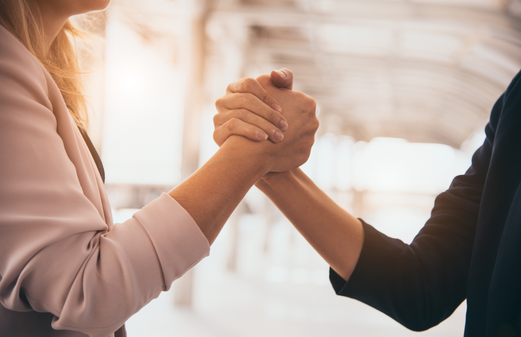 Nahaufnahme zweier Hände (Handschlag), die sich festhalten und übereinander greifen, als Symbol für Zusammenarbeit, Partnerschaft und Unterstützung.