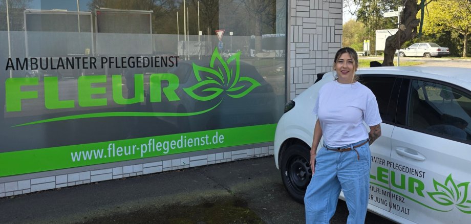 Inhaberin und Pflegedienstleiterin Kristina Baumgarten steht vor Firmengebäude von Ambulanter Pflegedienst Fleur GmbH, neben Firmenauto und Schaufenster.