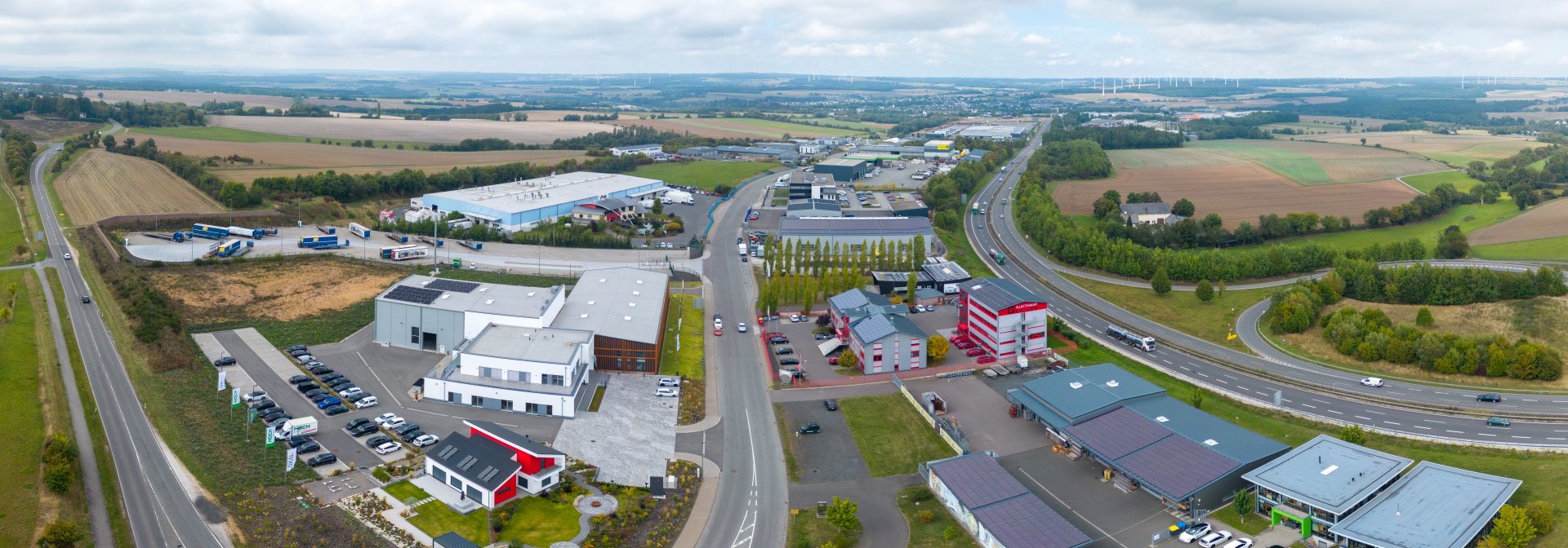 Luftaufnahme des Gewerbegebiebts im Industriepark Simmern mit Büro- und Produktionsgebäuden, Parkflächen, Zufahrtsstraßen sowie angrenzender B50 im Hunsrück.
